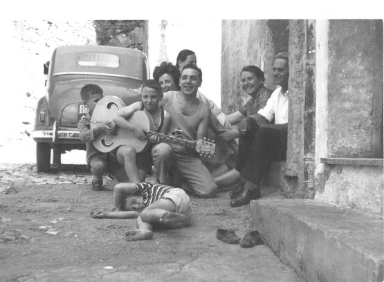Giovanni as a child with his father and family, holding his father's guitar